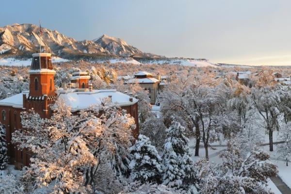 在一个阳光明媚的冬日，砖房Old Main被雪覆盖.