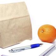 Brown Bag lunch next to a notepad, pen and orange